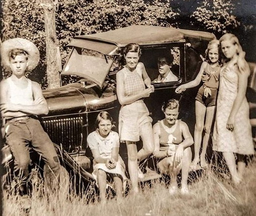 sepia toned portrait of family around a Model T