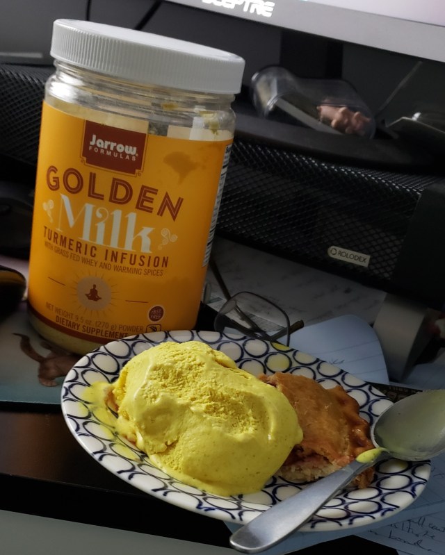 A jar of golden milk powder and a scoop of golden milk ice cream on a piece of cherry pie