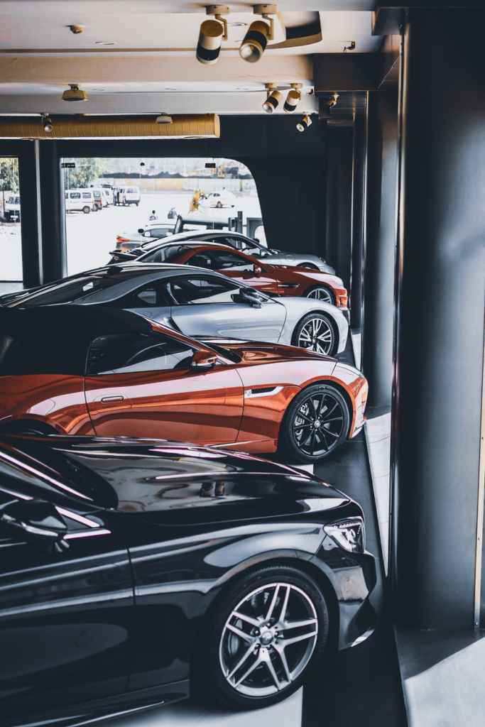 multiple high end cars parked in a garage.