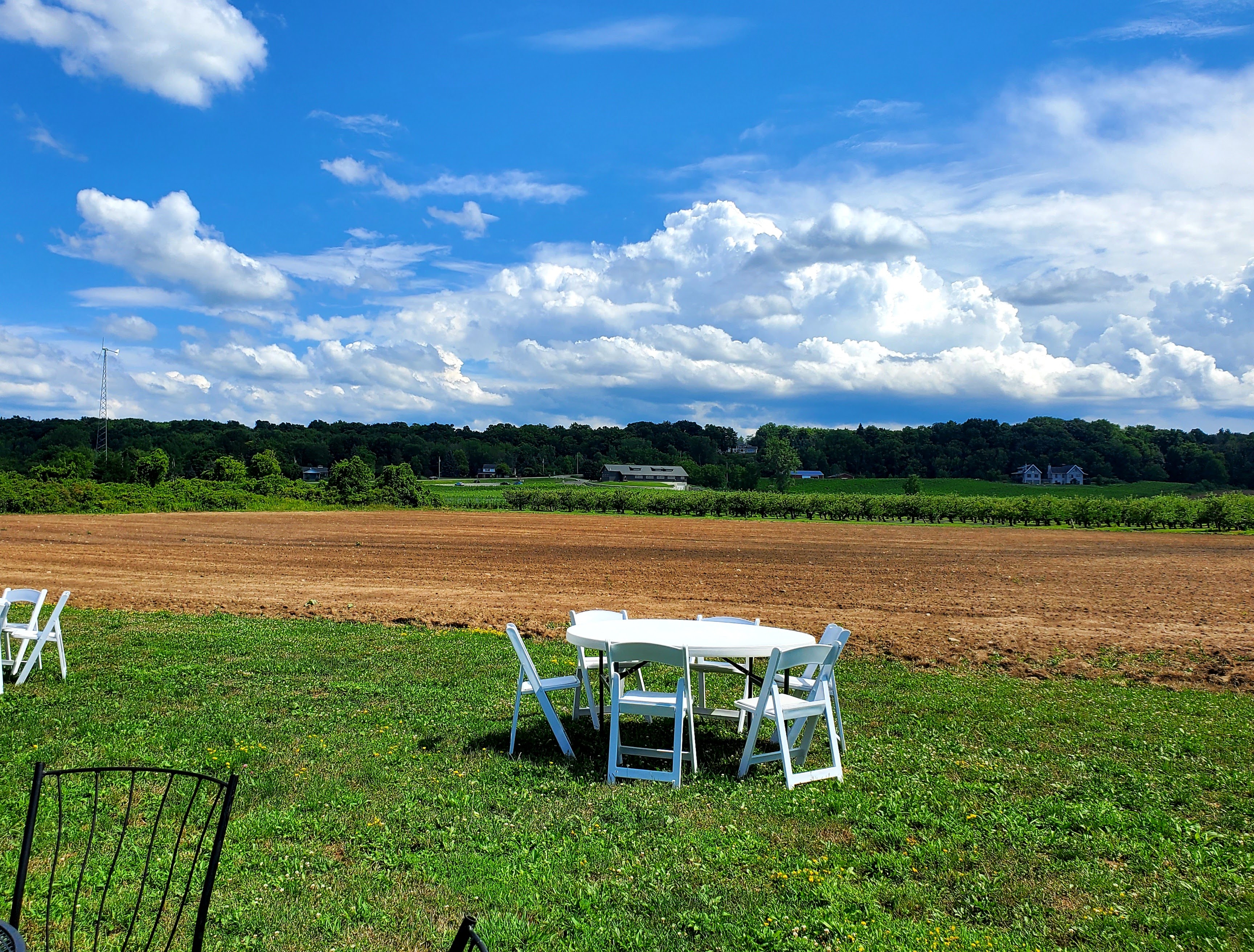 Table and chairs overlooking tilled land and Arrowhead Winery in the distance