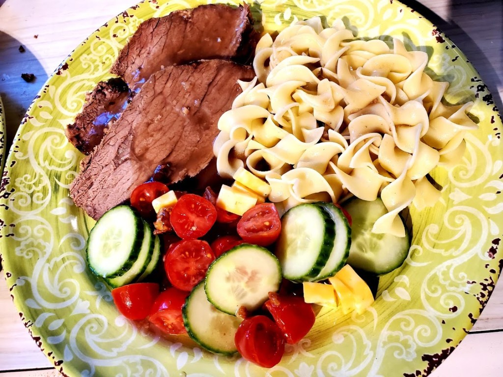 roast beef with gravy, noodles and a tomato and cucumber salad