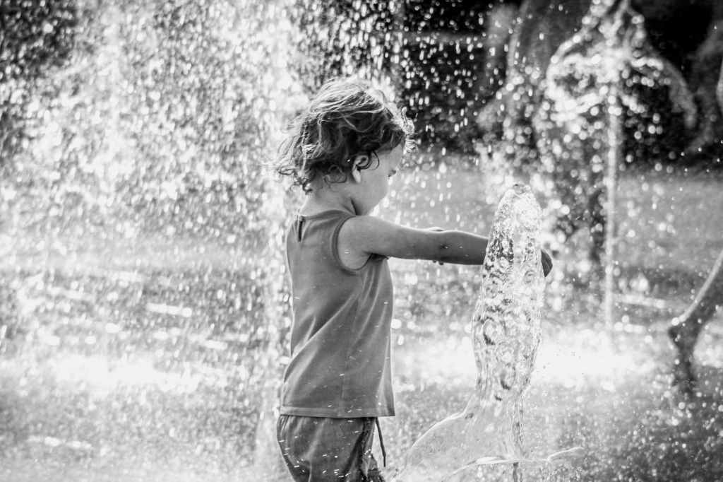 small child playing in a fountain