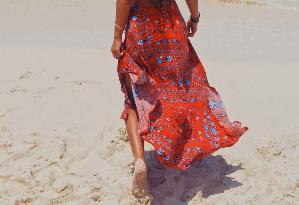 Woman walking on the beach in a colorful skirt
