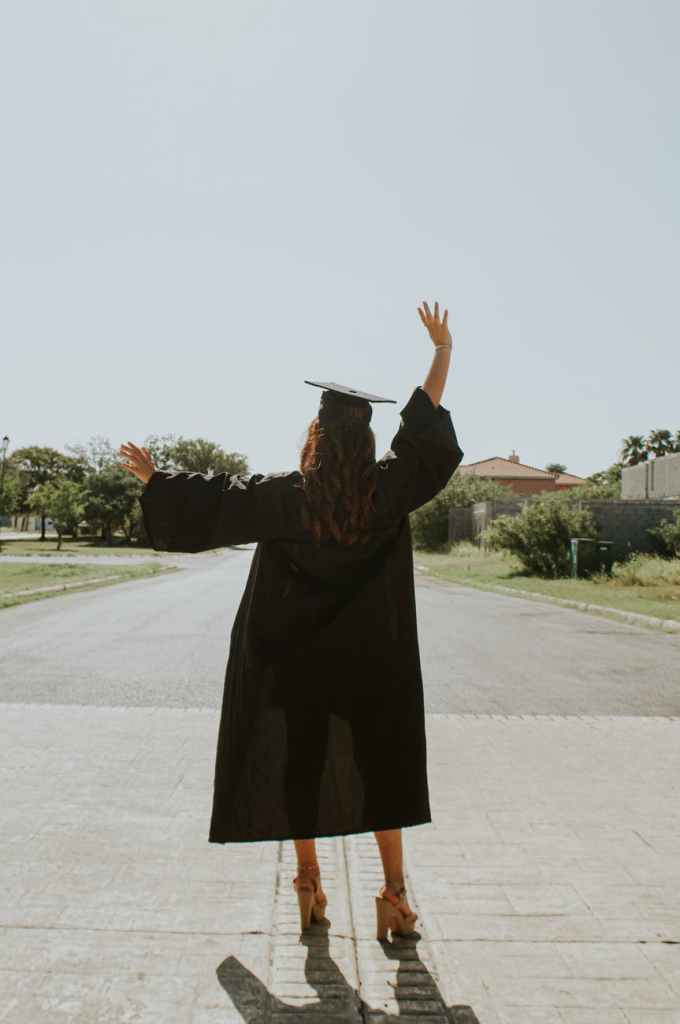 Young girl with cap and gown on, waving